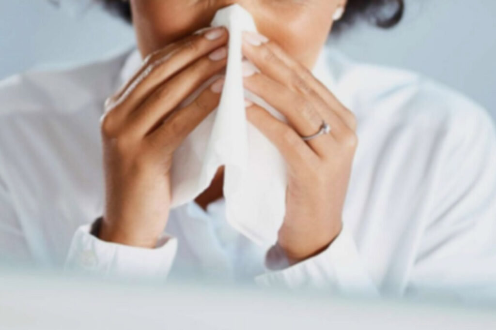 Woman blowing her nose. Sneezing, runny nose, coughing, are some of the common symptoms of mold exposure.